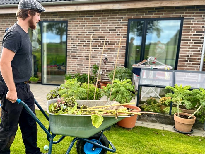 Søren Salomon Pedersen samler planterester sammen og putter dem i kompostspanden. Foto. Privat