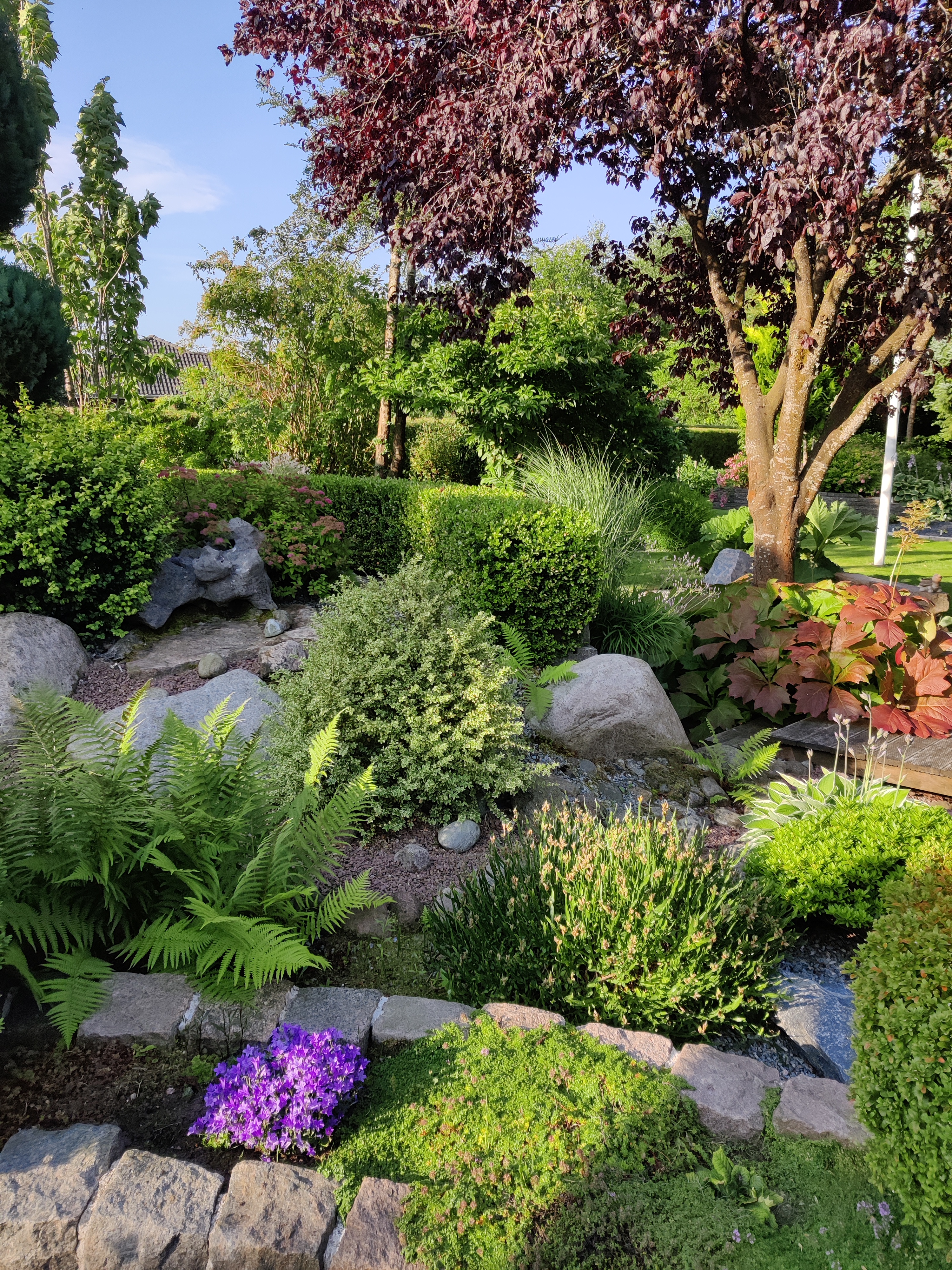 Havedesign med store sten, terrasser og bede