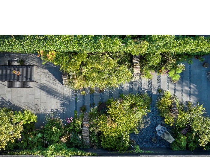 Fra denne vinkel ser man de mange fine designløsninger. Haven er delt op i 3 dele med terrassen nærmest huset (tv.), midterdelen er stort set fyldt ud med planter, og for enden ned mod haveskuret er der endnu en siddeplads. Bemærk også de markante brændestabler, der arkitektonisk skærer igennem beplantningen. Foto Alister Thorpe.