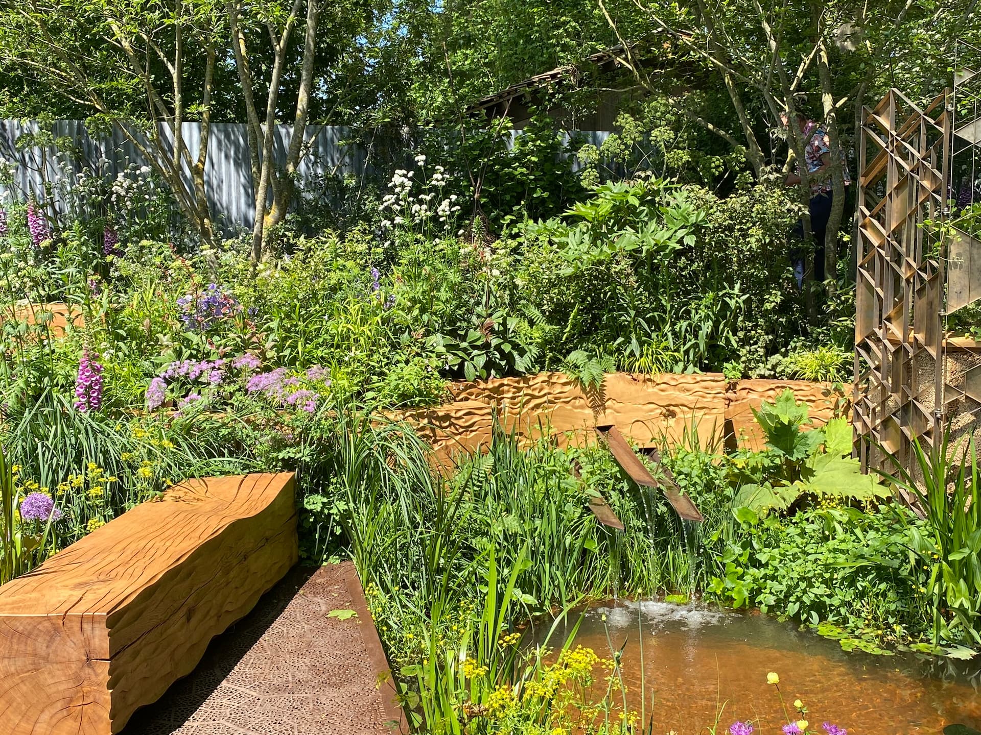 En stamme far et egetræ er bearbejdet og udgør en bænk i haven, hvorfra man kan høre rislen af regnvand som opsamles i et bassin i haven. Foto: Haveselskabet