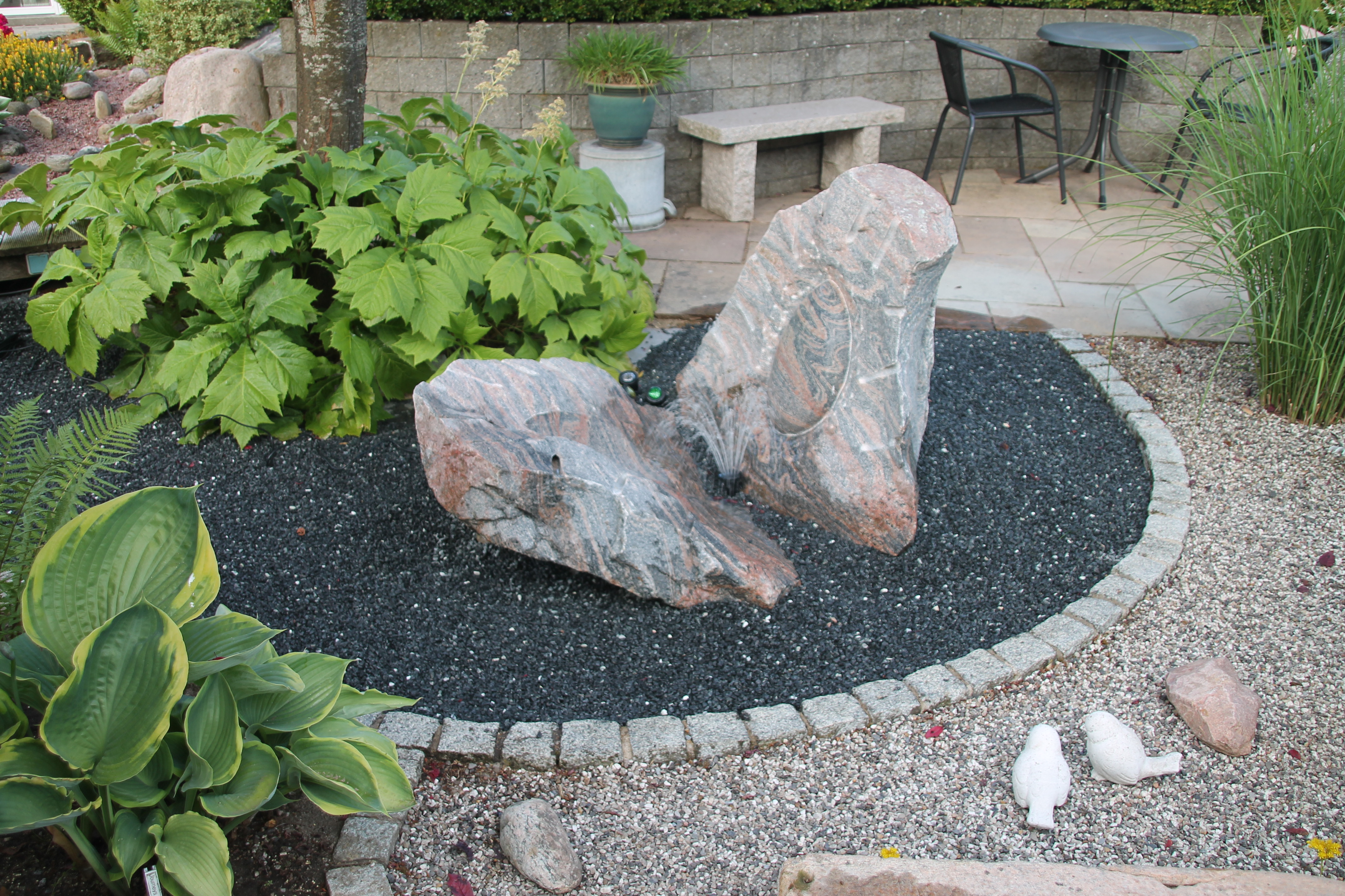 Havedesign med sten, træer, buske, terrasser og bede