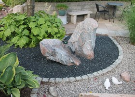 Havedesign med sten, træer, buske, terrasser og bede