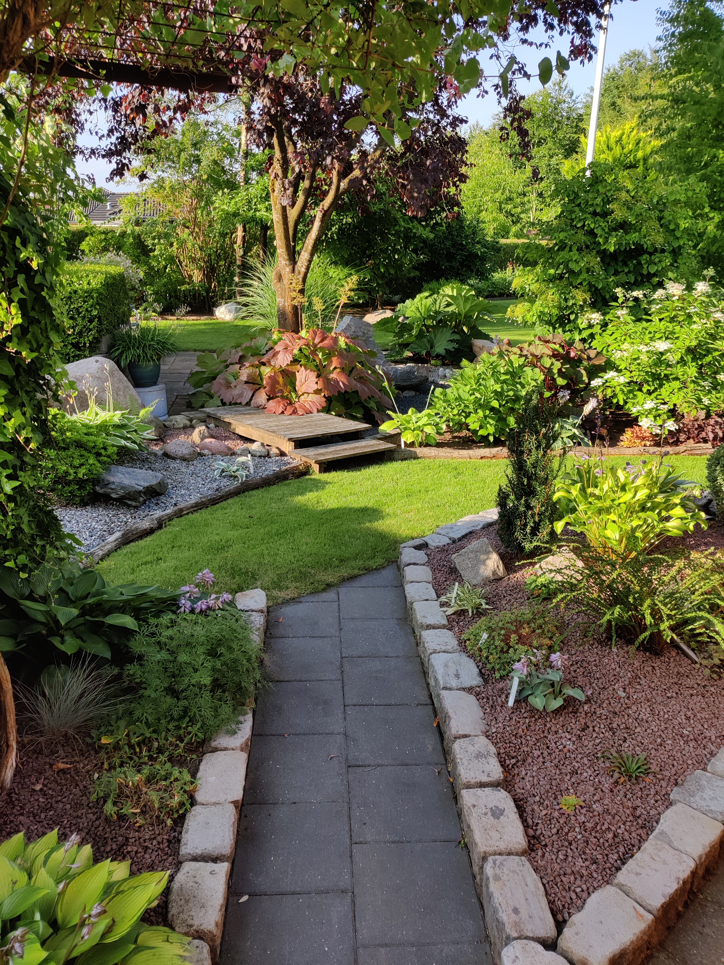 Havedesign med sten, træer, buske, terrasser og bede