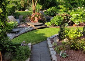 Havedesign med sten, træer, buske, terrasser og bede