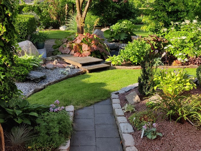 Havedesign med sten, træer, buske, terrasser og bede