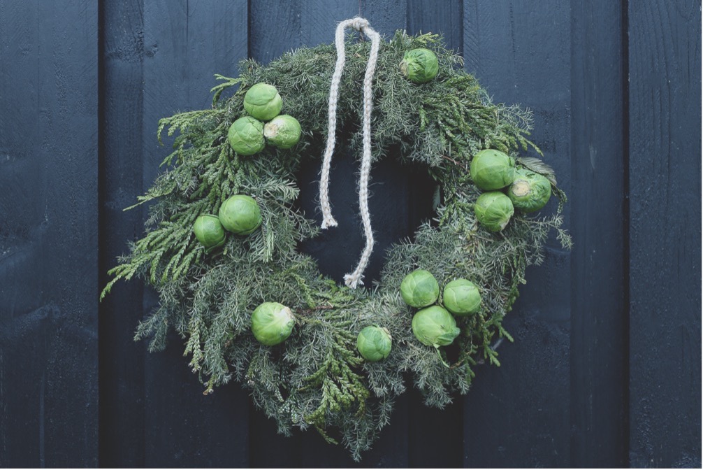 Krans af kransecypres, Chamaecyparis pisifera ‘Squarrosa’, og hønsebenstræ, Thujopsis dolabrata, viklet om en færdig grankrans og pyntet med rosenkål. Foto: Karina Emilie Revsbæk Lauesen